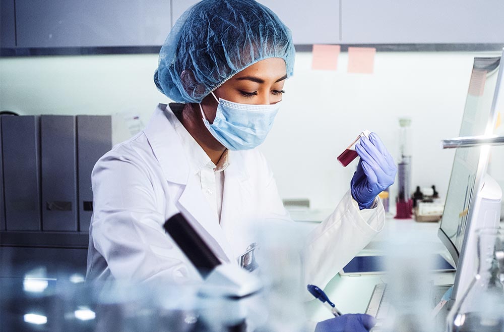 Woman in lab with mask on looking at a vial